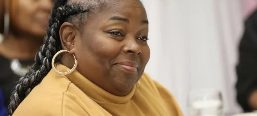 A guest in a mustard sweater smiles warmly