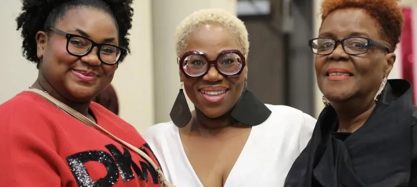 Three friends in glasses smile side by side